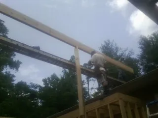 Carpenter setting a ridge beam over a new addition frame — Ice Dam Removal by Roofing Brothers in Ennis