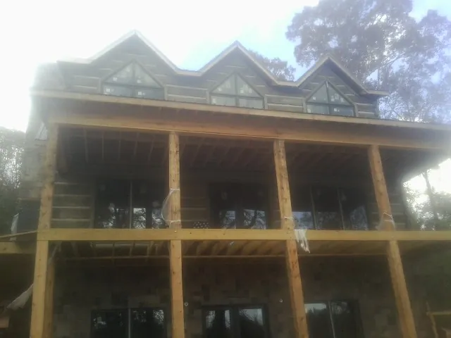 Dormers and porch framing on a large log home under construction — Roof Coating work by our crew in Ennis