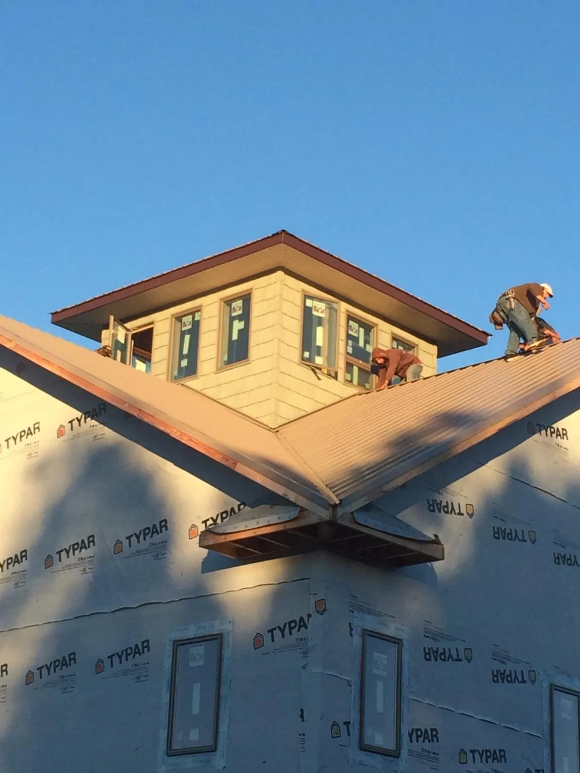 Roofers working around a rooftop cupola on a new metal roof at sunset — Roof Waterproofing in Ennis by Roofing Brothers